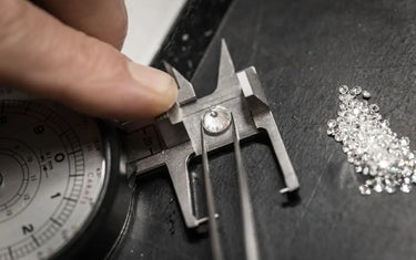 Measuring a loose round diamond using precision jewelry tweezers and a gem gauge.
