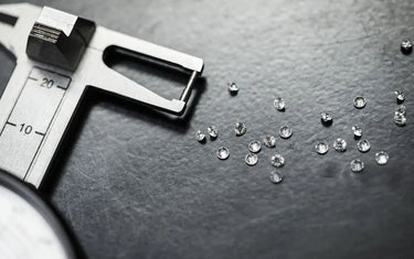 Loose diamonds scattered on a workbench next to a precision gemstone caliper gauge.