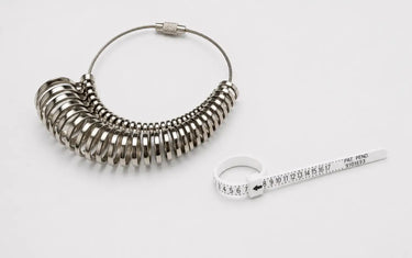 A metal ring sizer gauge loop next to a white plastic zip-style ring measuring belt.