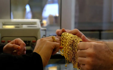 Hands holding heavy gold chain necklace during over the counter jewelry appraisal