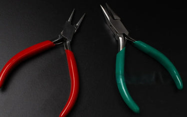 Red-handled round nose pliers next to green-handled chain nose pliers displayed on a clean black background.
