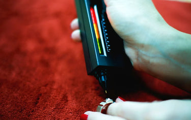 Close up of a person using a handheld electronic testing selector pen on a diamond ring with red background