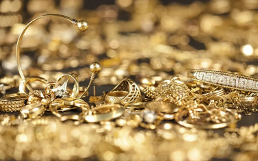 A large pile of assorted gold jewelry including rings, bracelets, and bands scattered together.