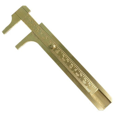 A small brass slider caliper showing millimeter and inch markings on the scale, slightly open.