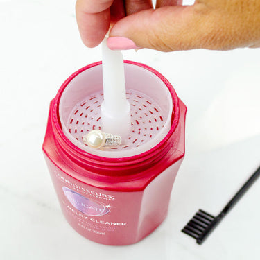 Hand using the dip tray to safely clean a delicate pearl strand in Connoisseurs Delicate Jewelry Cleaner.