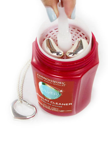 Hand using the dip tray to clean silver jewelry inside the Connoisseurs Silver Jewelry Cleaner jar.
