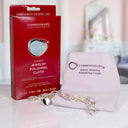 A polished silver heart bracelet resting on a Connoisseurs jewelry cloth next to its red box.