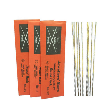 Three orange packets of Golden Swords jewelers' saw blades next to a bundle of loose steel blades.