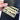Handheld view of the slim Alfa Mirage diamond gauge being pulled from a leather wallet.