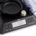 Close-up of the KP-601 weighing pan, protective shield, and the included 100g chrome calibration weight.