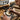 Engraver using an air-assisted pneumatic graver handpiece to carve a detailed lion relief on a brass plate.
