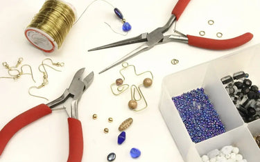 Jewelry pliers with gold wire, earring hooks, and beads for DIY wire wrapping and jewelry making.