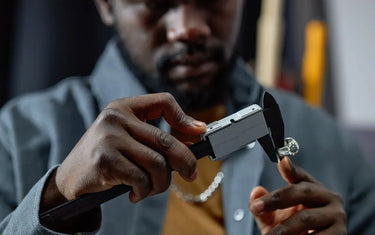 A jeweler measuring a silver ring using a digital caliper.