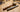 Rawhide mallet and steel ring sizer mandrel lying on a wooden jewelry-making workbench.