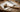 Rawhide mallet lying on a sheet of silver metal with strips and jewelry-making tools on a wooden workbench.
