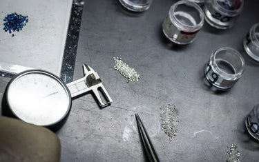 Loose diamonds being sorted and measured with an analog gem gauge and tweezers.