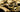 A collection of various gold jewelry including textured rings and intricate chains on a dark background.