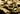 A collection of various gold jewelry including textured rings and intricate chains on a dark background.