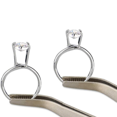 Tweezers holding silver try-on ring gem holders securely clasping round brilliant diamonds.