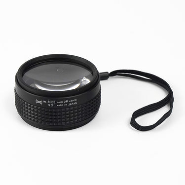 Front-angled view of the 5x Alfa Mirage Hand GR Loupe No. 3005 with attached security wrist strap.