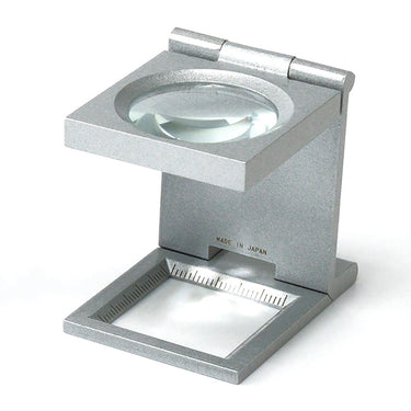 Close-up of an Alfa Mirage linen tester showcasing the high-clarity optical glass lens for precision inspection.