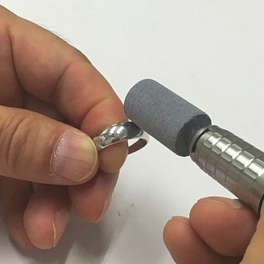 Rotary tool with a grey Alfa Mirage PVA point being used by hand to polish a silver ring.