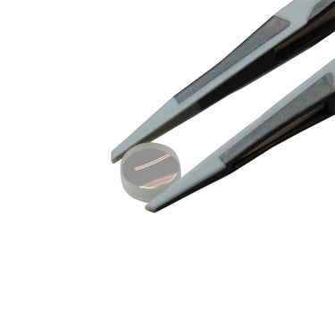 Close-up of Alfa Mirage D-MASTER soft polymer tips securely gripping an optical glass lens without scratching.