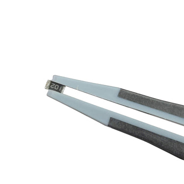 Precision soft tips of Alfa Mirage D-MASTER tweezers holding an electronic SMD chip resistor.