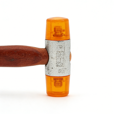 Macro detail of translucent amber orange polymer head mounted on cast metal mallet body.
