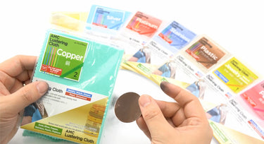 Hands holding AMC Copper Lustering Cloth and a polished metal piece showing cleaning results.