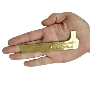 A compact brass pocket caliper held flat in a person's open palm to demonstrate its small size.