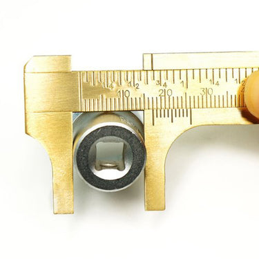 A brass slider gauge measuring the outside diameter of a metal socket wrench piece.