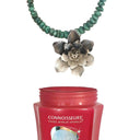 A tarnished silver flower pendant on a turquoise bead necklace shown above the Connoisseurs Silver Cleaner jar.