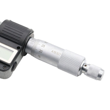 Detailed view of the knurled metal thimble and vernier scale markings on a digital micrometer.