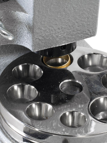 Close-up of gold ring being compressed in the Durston ring reducer multi-hole reduction plate.