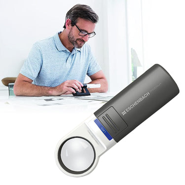 A man using the Eschenbach Mobilux LED magnifier with a Mobase stand for reading newspapers.