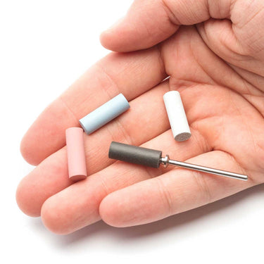 A person holding four silicone polishers in their hand, with one mounted onto a metallic mandrel pin.
