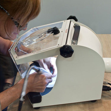 Artisan using a rotary handpiece inside the Foredom lighted work chamber enclosure.