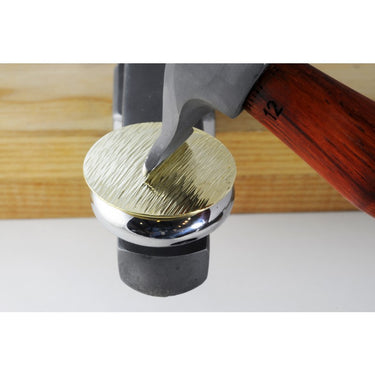 Fretz HMR-12 hammer applying sharp parallel linear texture to a round brass metal disc on a stake.
