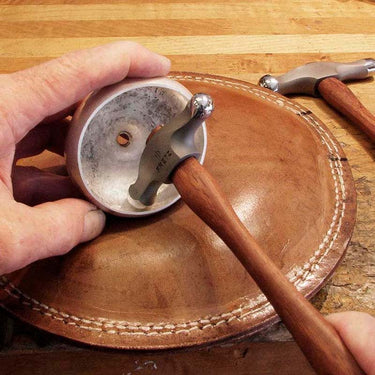 Metalsmith sinking and shaping metal bowl into a leather sandbag using Fretz HMR-4 hammer.