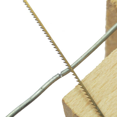 A Golden Sword jeweler's saw blade making a precise cut into a round metal wire over a wooden bench pin.