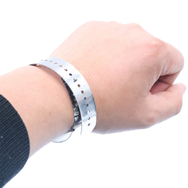 A metal bracelet measuring band wrapped around a person's wrist to check circumference size.