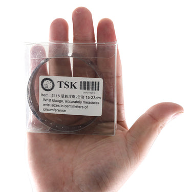 A person holding the boxed TSK wrist gauge tool showing the 15-23cm measurement product label.