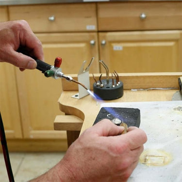 Jeweler using Miller Smith The Little Torch with micro flame for precision jewelry soldering on a soldering block.