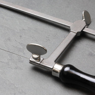 Close-up detail of the lower thumbscrew blade clamp assembly directly above the black handle ferrule.