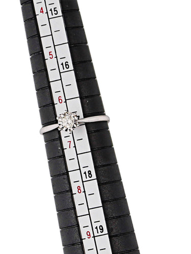 A diamond engagement ring placed on the black plastic measuring stick mandrel to determine its size.