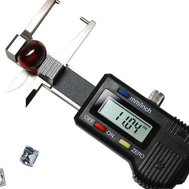 High angle shot of an electronic caliper measuring a dark red round gemstone bead showing an 11.04mm reading.