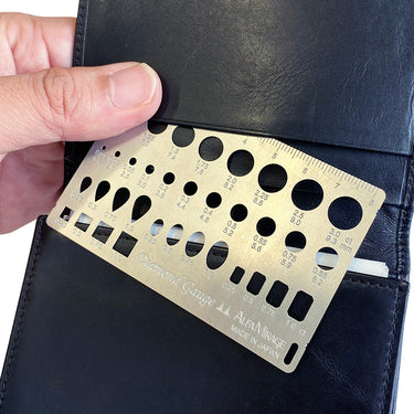 Handheld view of the slim Alfa Mirage diamond gauge being pulled from a leather wallet.