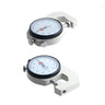 Two thickness dial gauges displayed from different angles showing the 0.1mm graduation white measurement face.