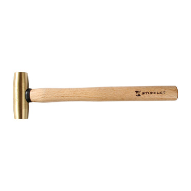 A Stuccler brass mallet with a wooden handle lying flat horizontally, head facing left.